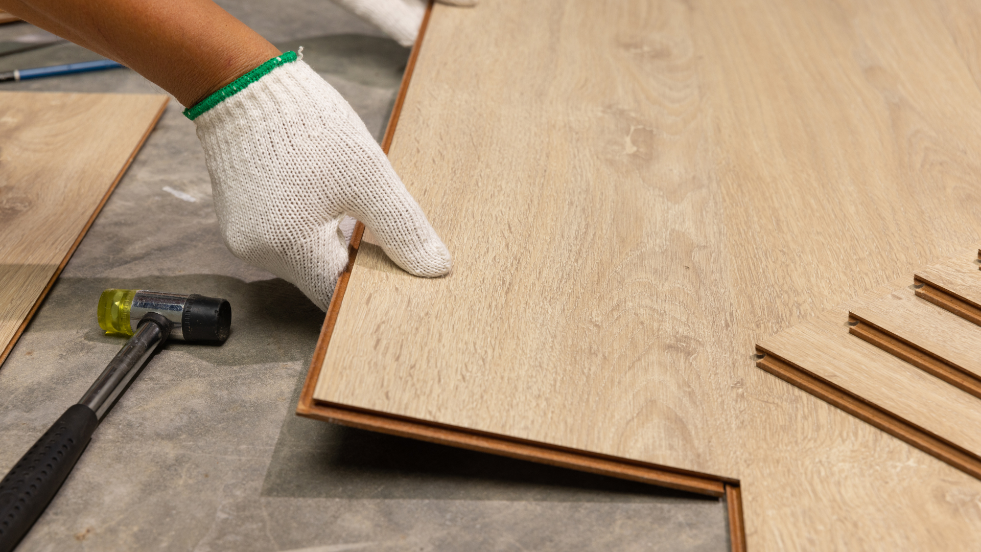 A person is installing a wooden floor with a hammer.