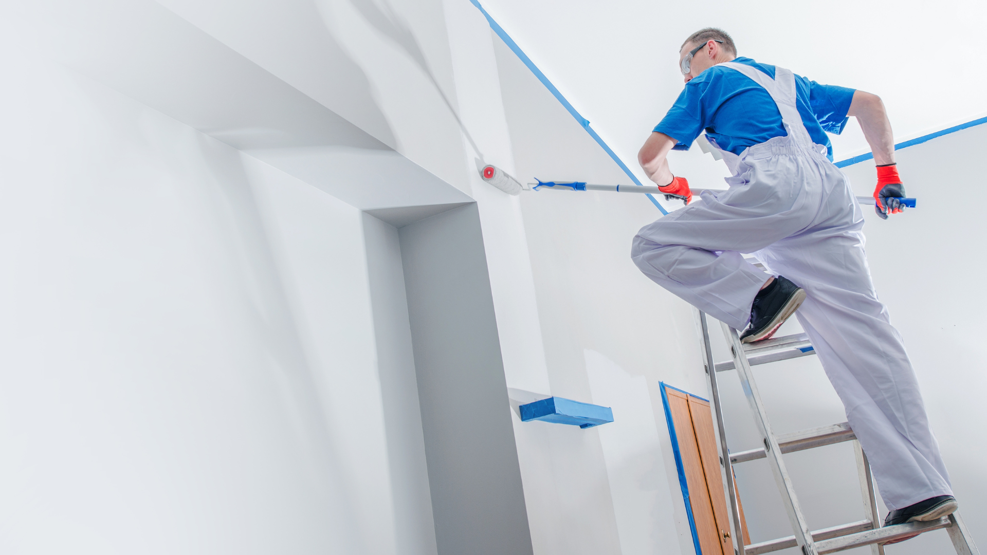 A man is standing on a ladder painting a wall.
