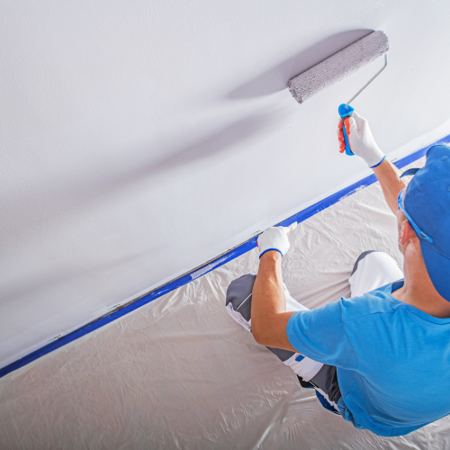 A man is painting a wall with a roller.