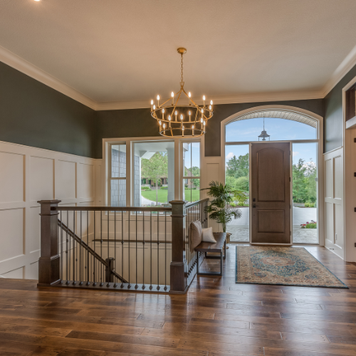 A hallway with stairs and a chandelier hanging from the ceiling