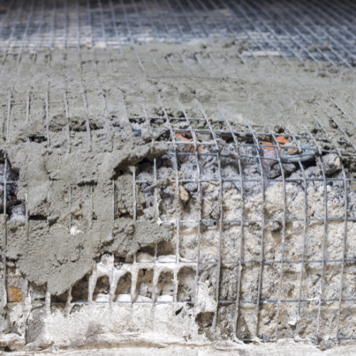 A close up of concrete being poured over a wire mesh.