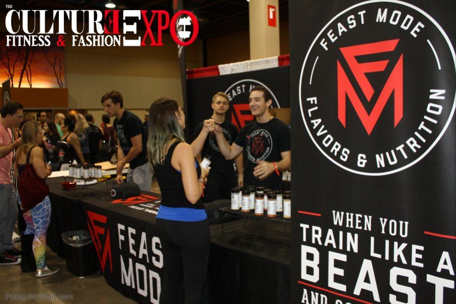 Fitness expo booth with Feast Mode Nutrition banner, staff handing out drinks, and people sampling products