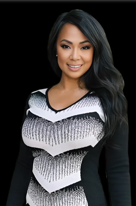 Portrait of a smiling woman in a black-and-white patterned dress against a black background