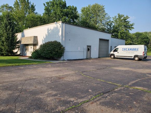 A white van is parked in front of a white building.