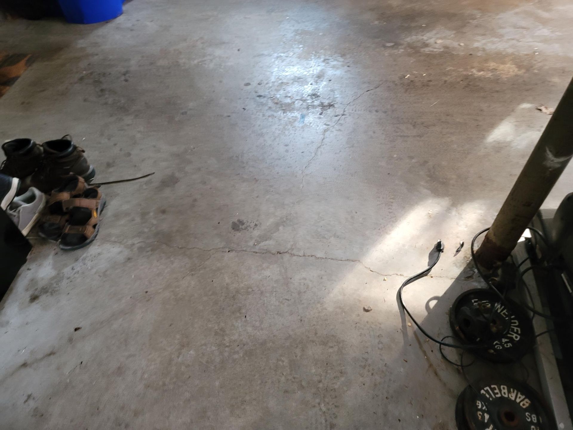 Concrete floor with shoes and weights. Sunlight, brown and gray tones.