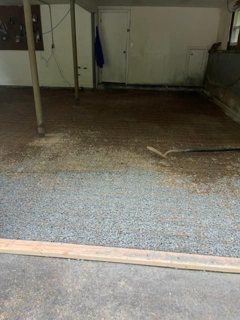 A gravel floor in a garage-like space, with a wooden border at the foreground.