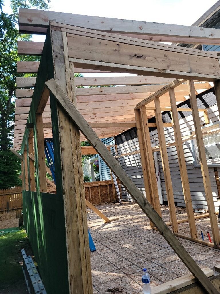A wooden structure is being built in the backyard of a house.