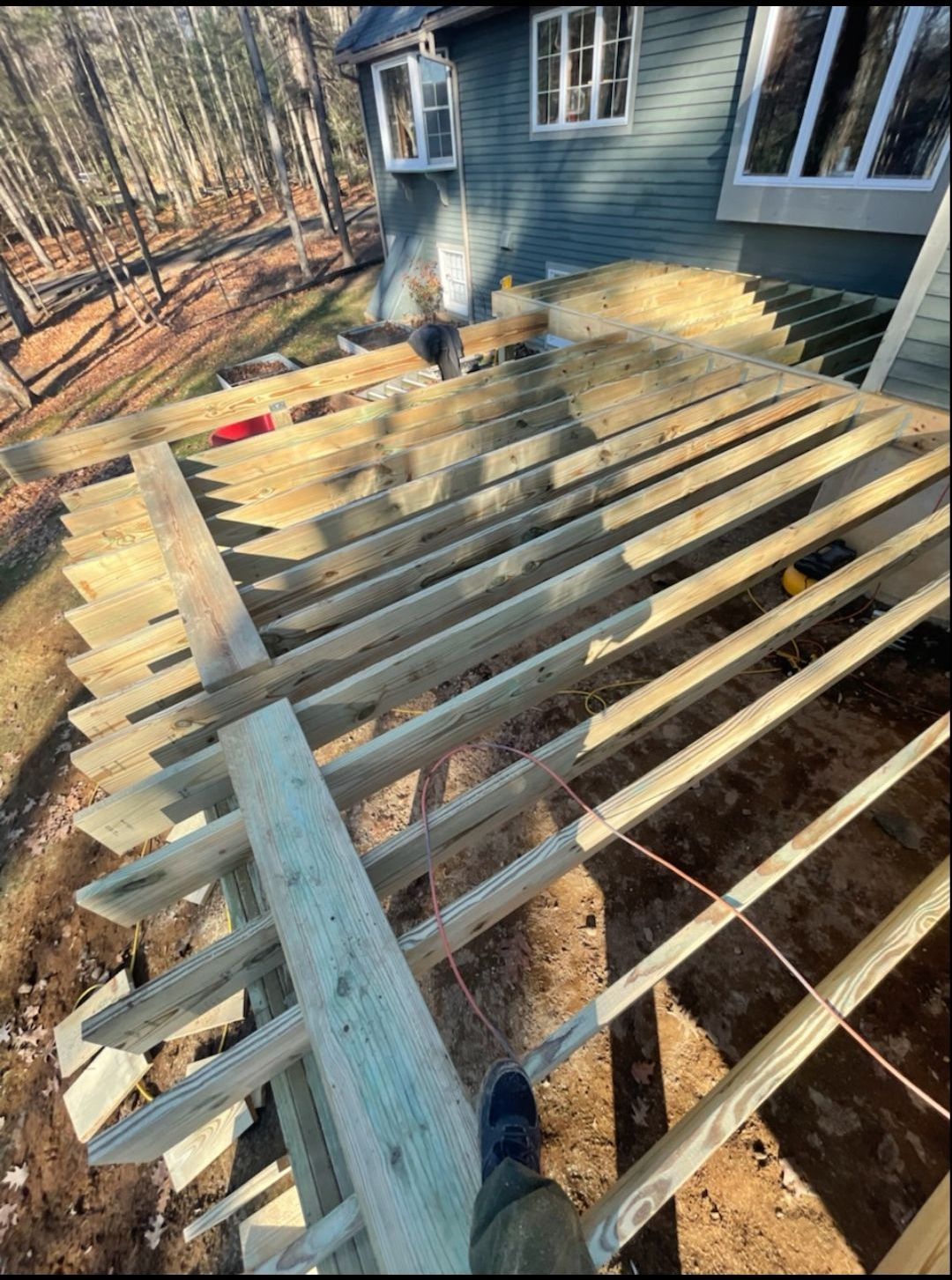 A person is standing on a wooden deck under construction in front of a house.