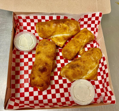 Four golden-brown pastries with dipping sauces in a red-and-white checkered box.
