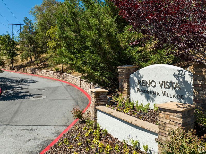 Entrance sign for Reno Vista Panorama Village with landscaped surroundings at Reno Vista Apartments.