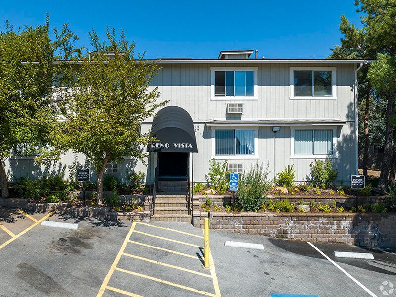 Two-story Reno Vista apartment building exterior with entry stairs, awning, and landscaping at Reno Vista Apartments.