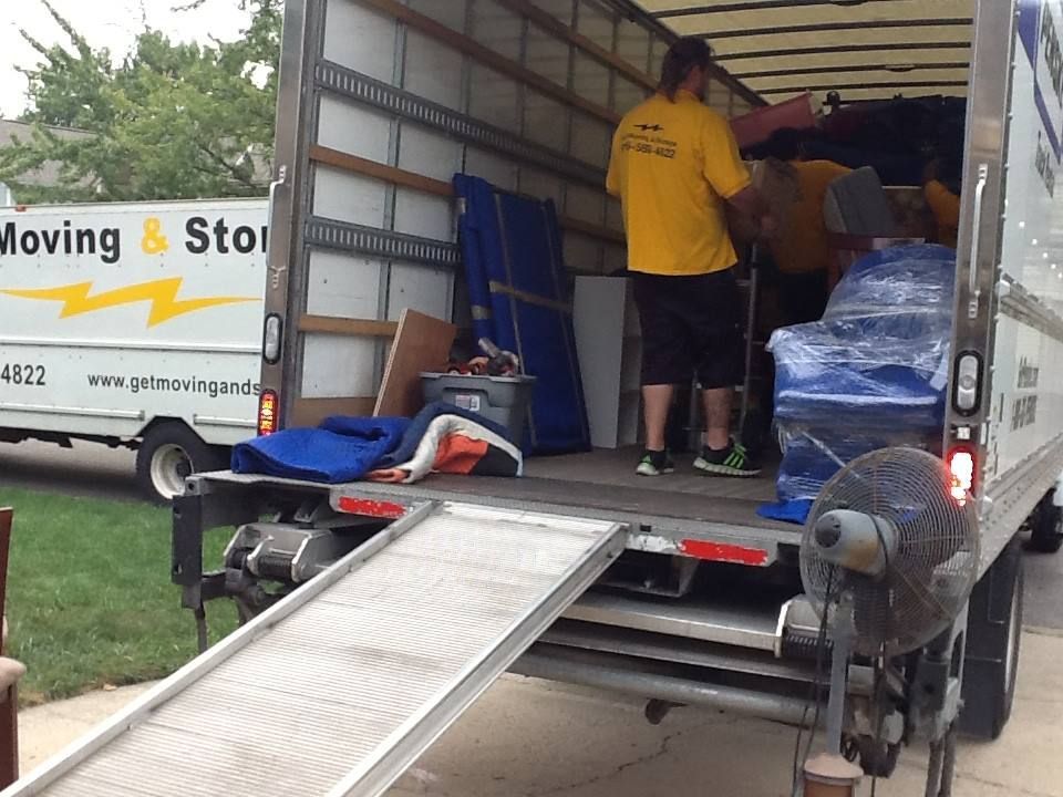 A man in a yellow shirt is loading a moving and storage truck