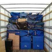 The inside of a moving truck filled with blue boxes and luggage.