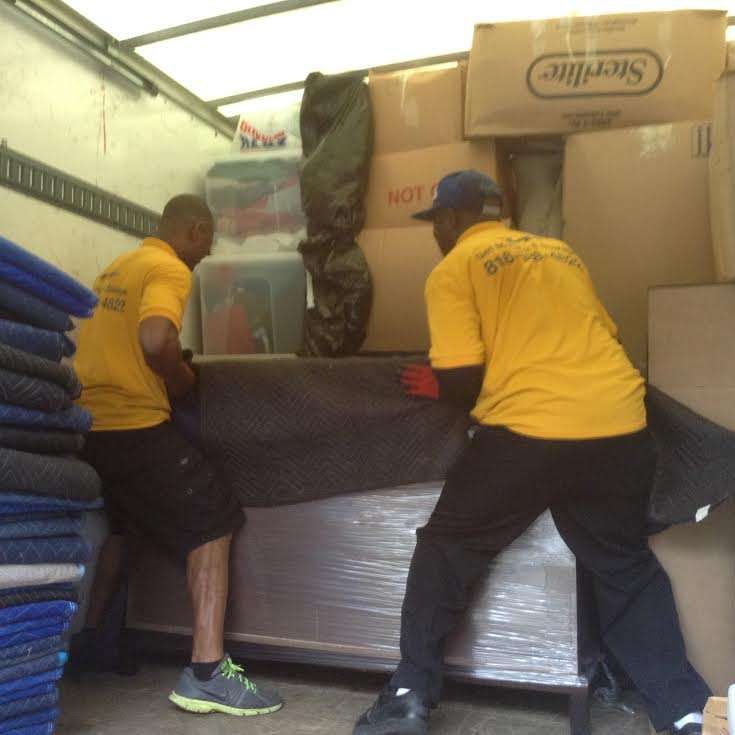 Two men in yellow shirts are loading boxes into a truck that says sterilite