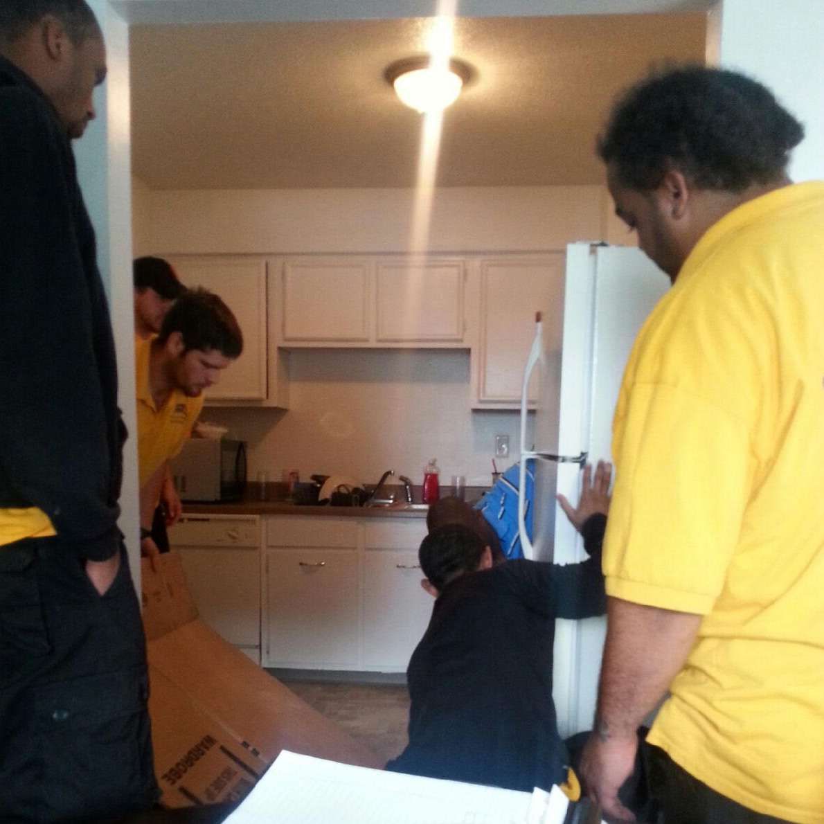 A man in a yellow shirt is standing in a kitchen