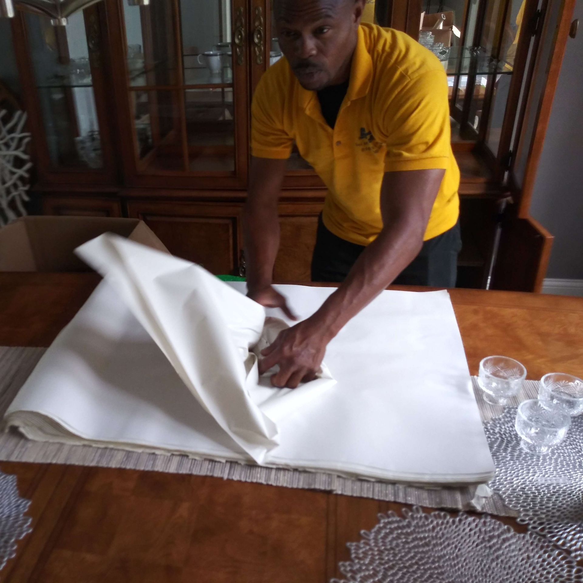 A man in a yellow shirt is working on a table