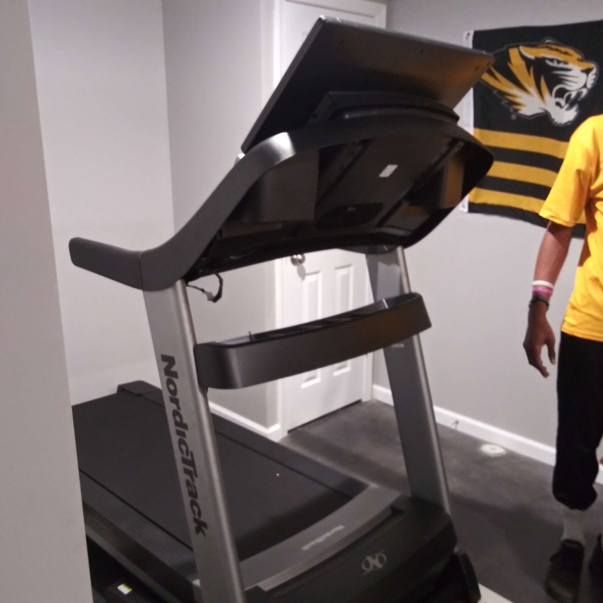 A man in a yellow shirt is standing next to a nordictrack treadmill
