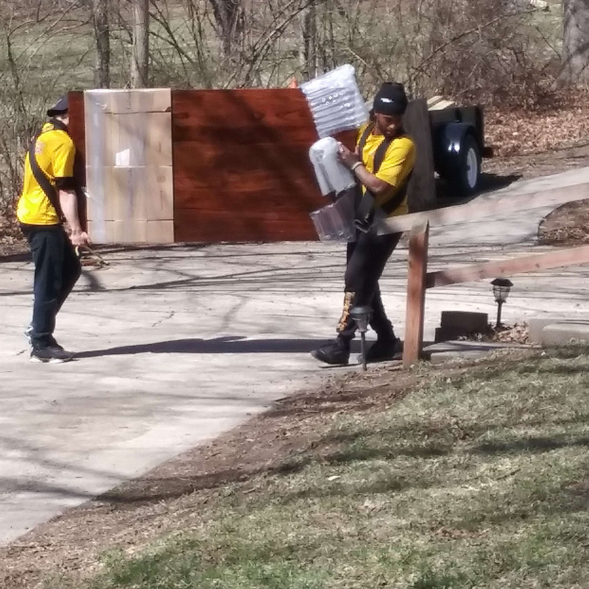 A man in a yellow shirt is carrying a box