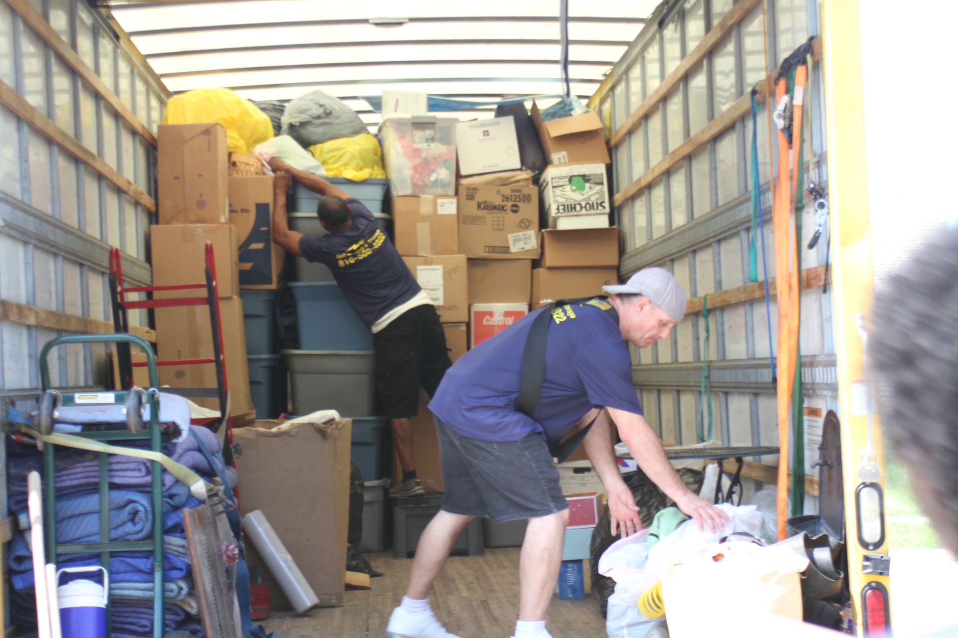 Two men are loading boxes into a moving truck