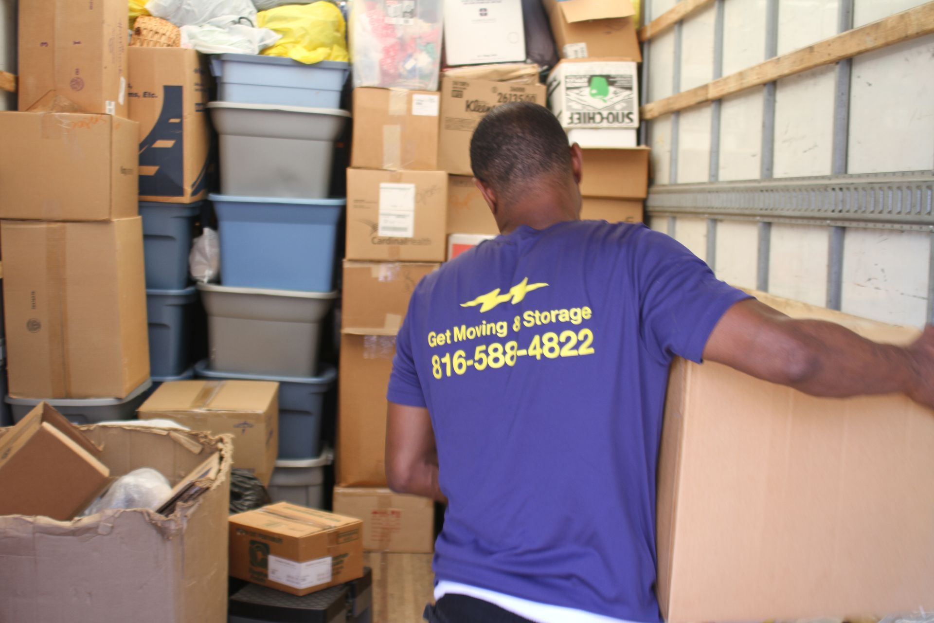A man wearing a purple shirt that says get moving storage