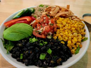 Colorful salad bowl with avocado, corn, black beans, tomatoes, tortilla strips, and quinoa.
