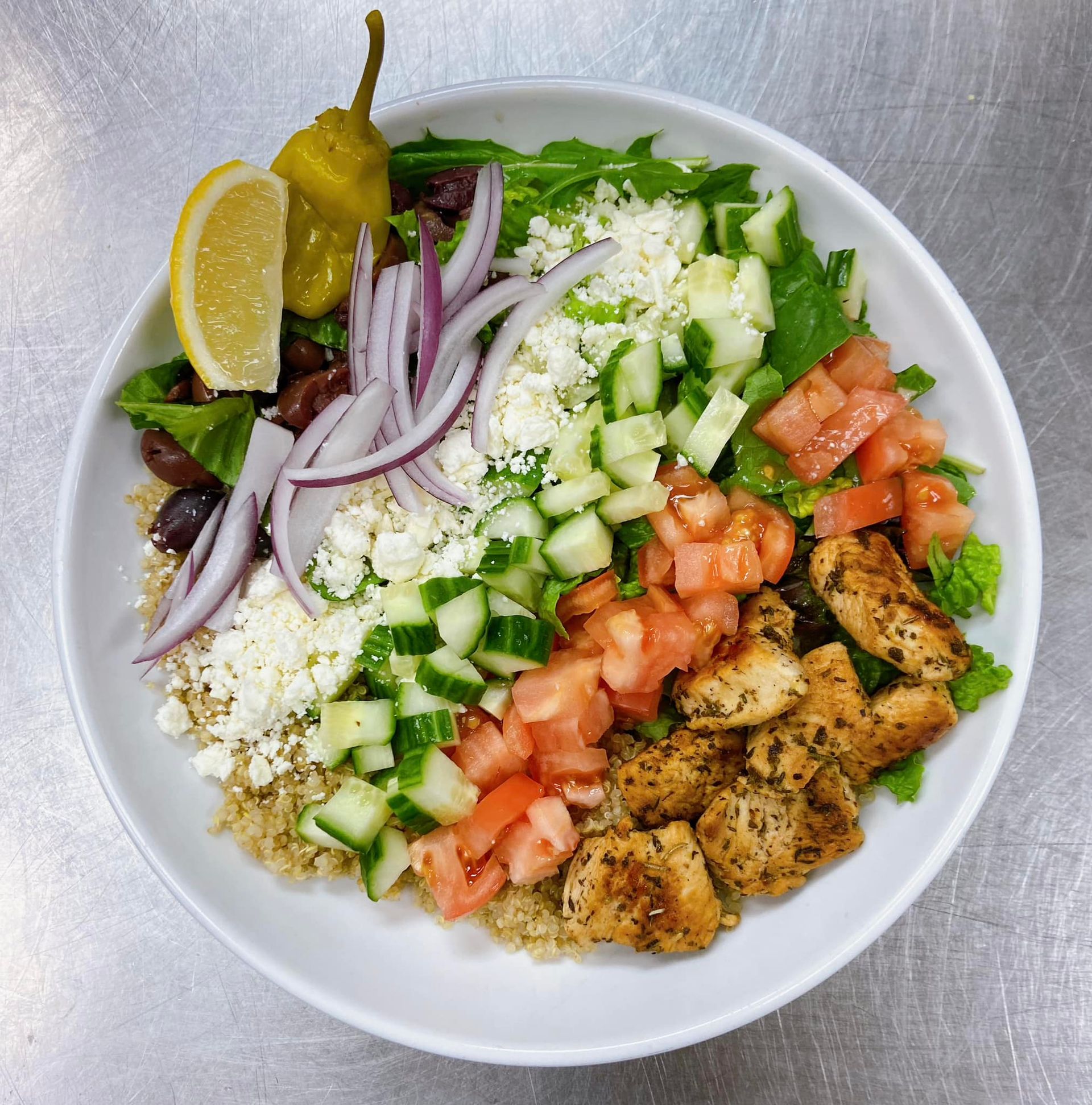 Greek salad bowl with chicken, vegetables, and feta cheese.
