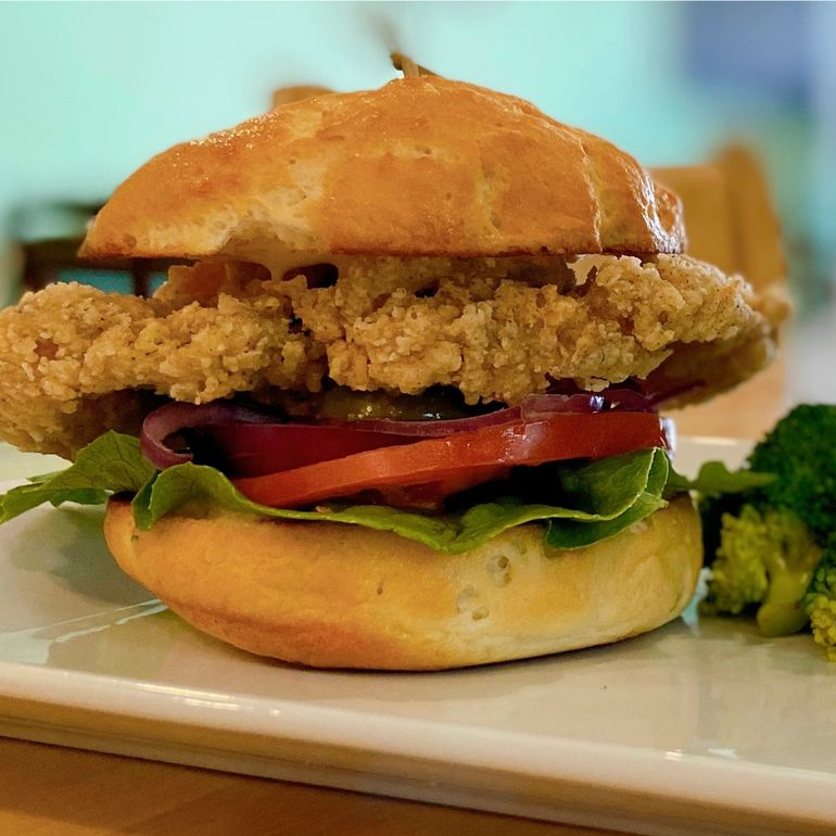Fried chicken sandwich with tomato, red onion, lettuce, and a side of broccoli.