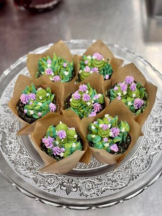 Cupcakes decorated with green and purple frosting, arranged on a silver platter.