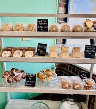 Display shelf with packaged baked goods, including cookies, muffins, and squares.