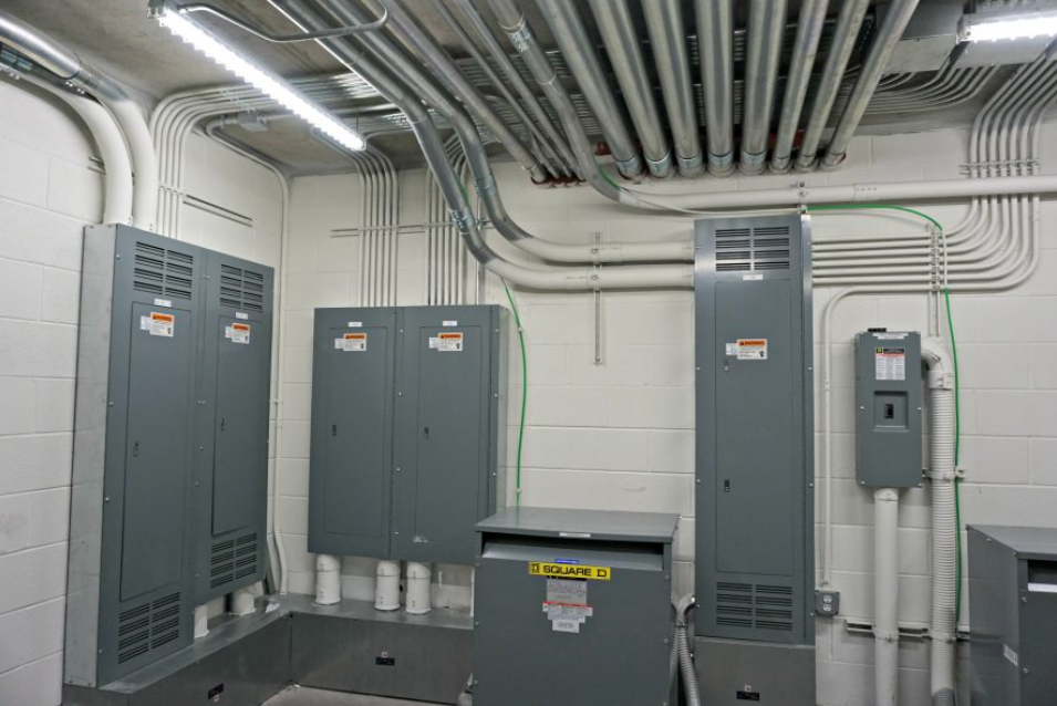 Electrical equipment room with gray panels, conduit, and overhead cable trays