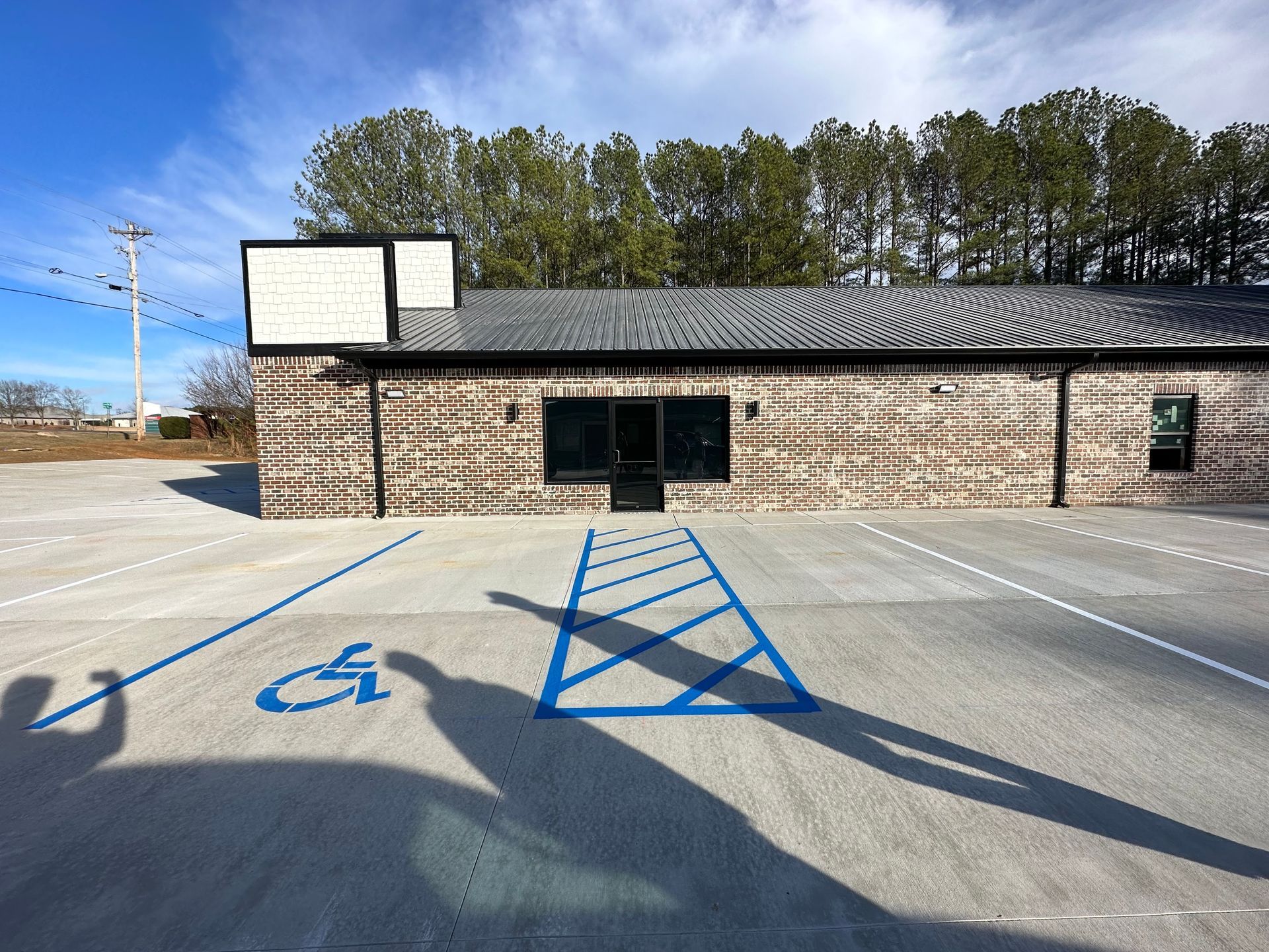 Exterior view of a brick building with a handicap parking spot marked with blue paint on a concrete surface.