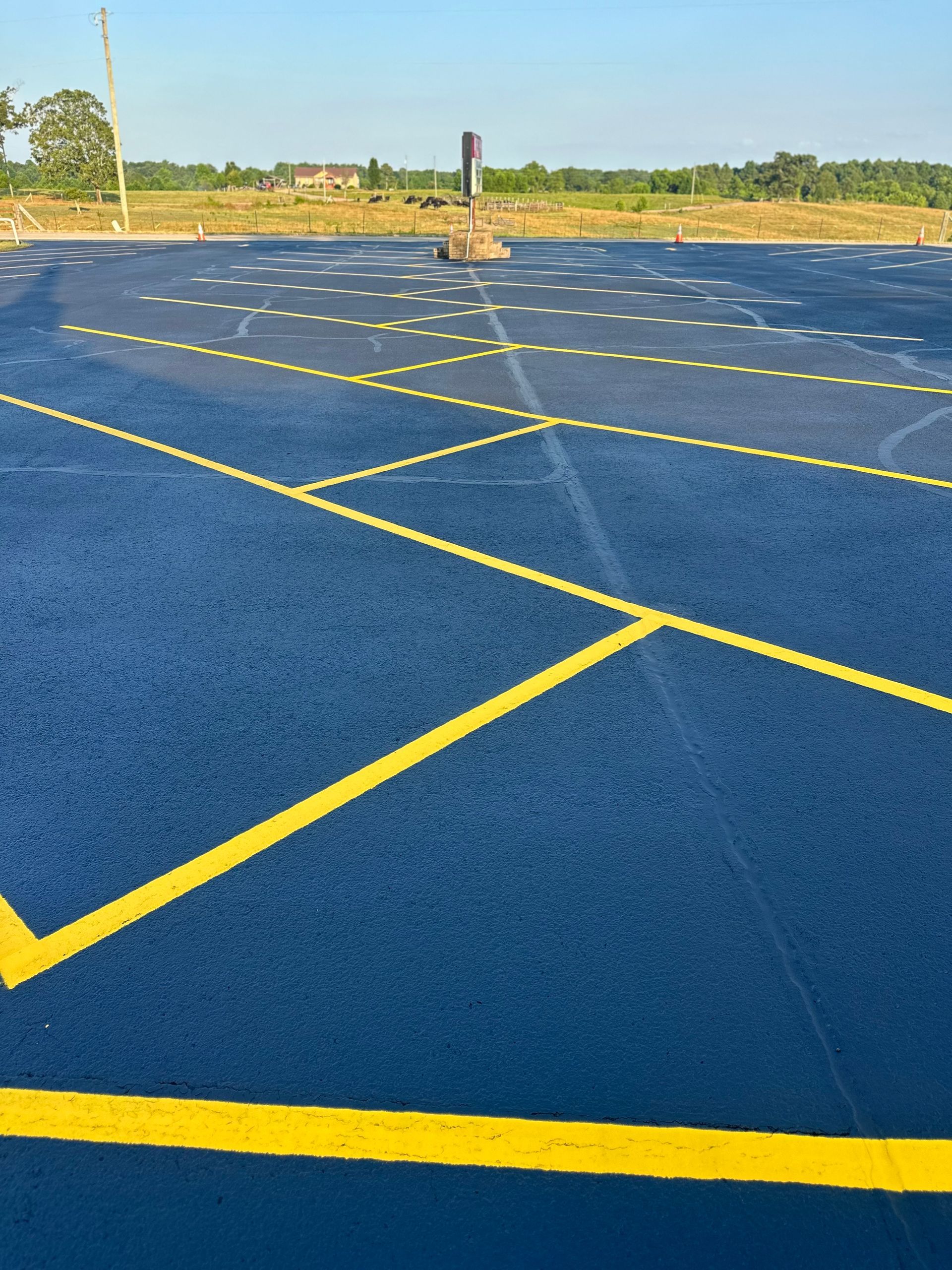 Blue asphalt surface with yellow lines, possibly a driving course or parking lot, in an outdoor setting.