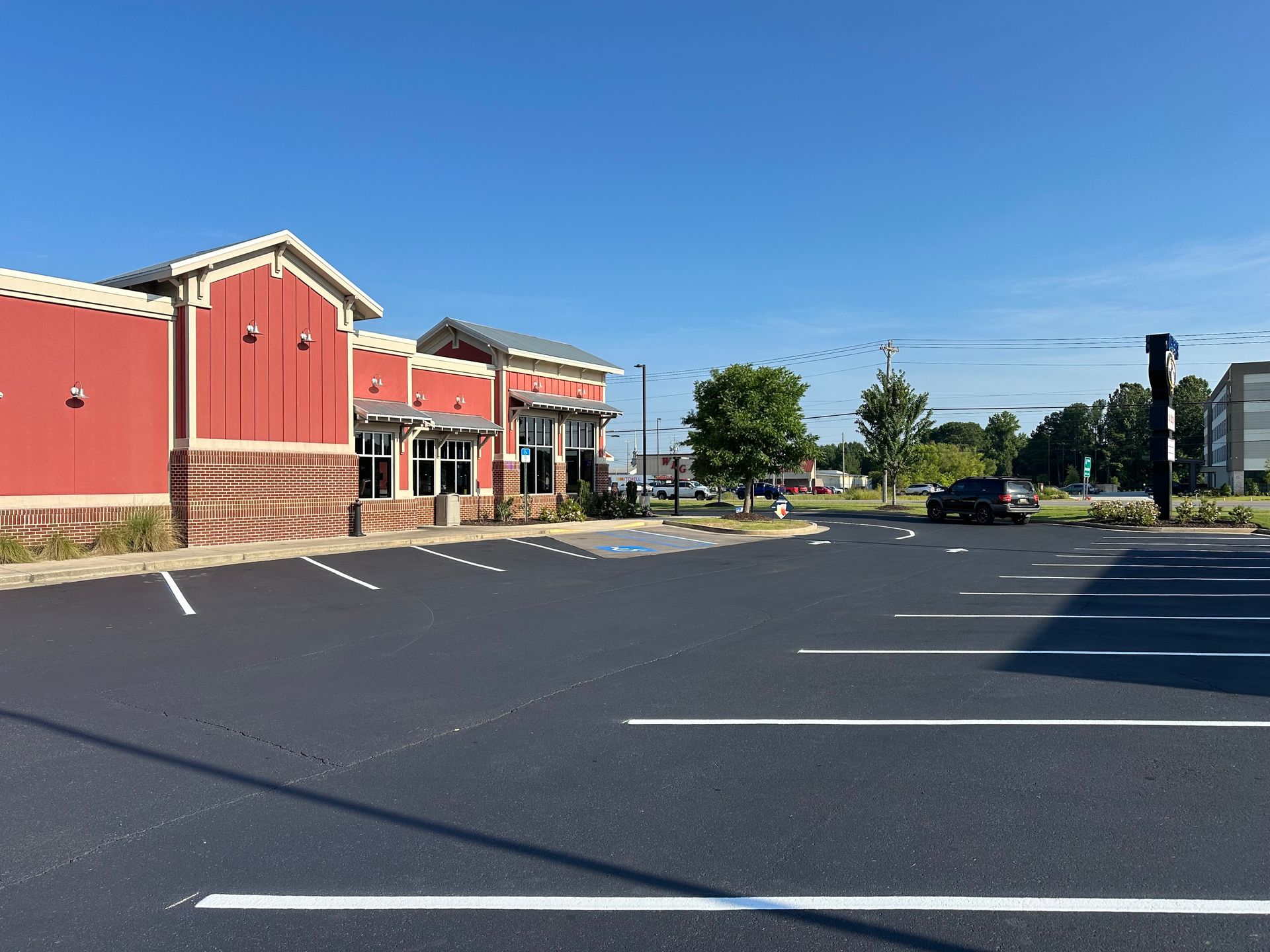 Exterior view of a red and brick building with an empty parking lot on a sunny day.
