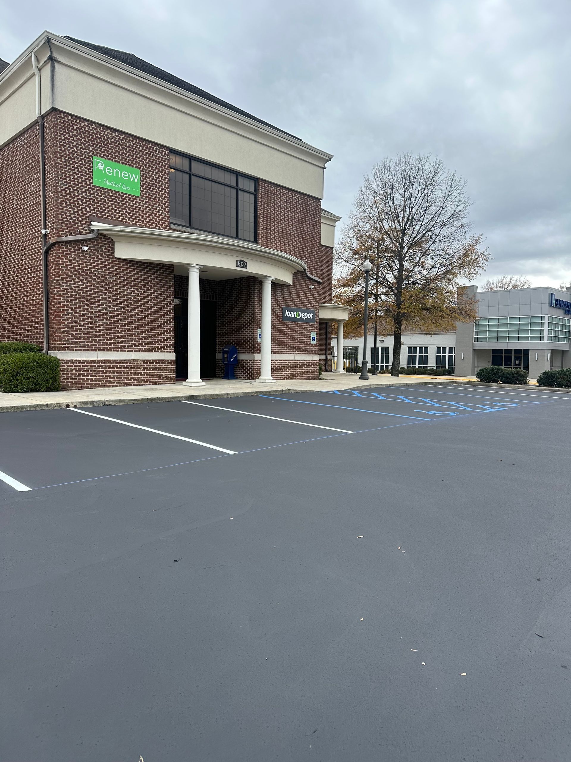 Building with brick facade, white columns, and parking lot on an overcast day.