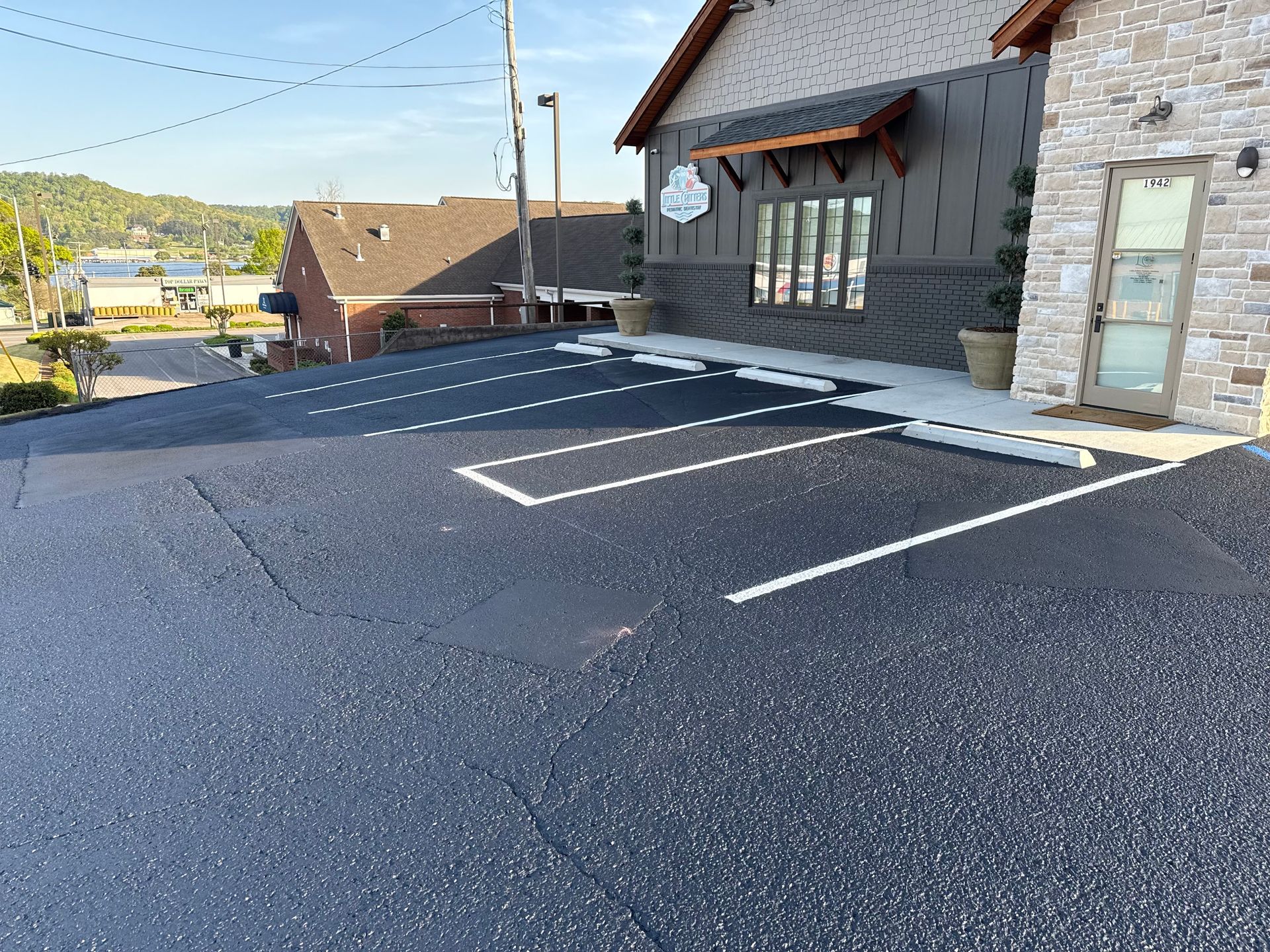 Asphalt parking lot with white painted parking space lines in front of a building.