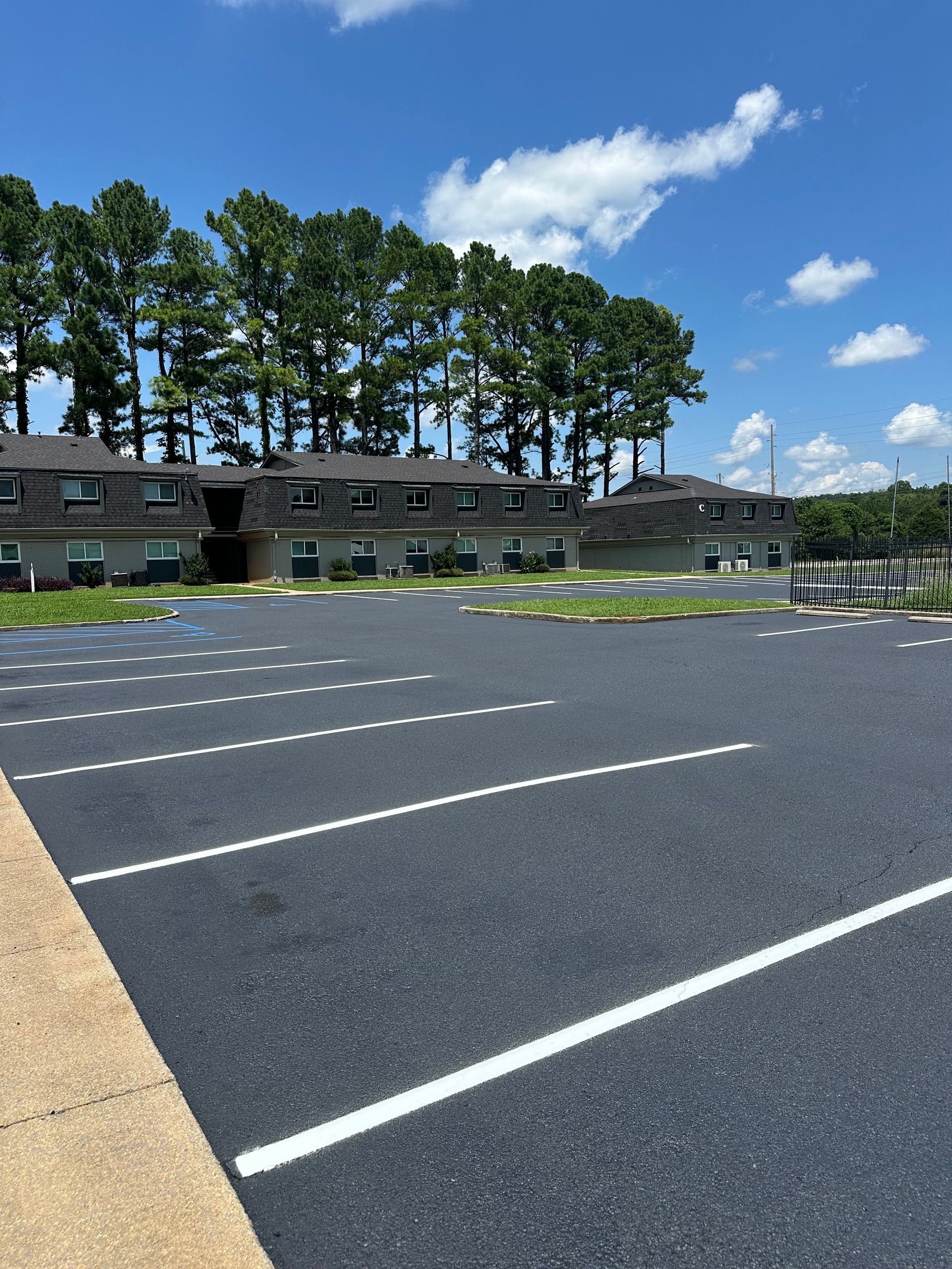 Apartment complex with a large parking lot on a sunny day.