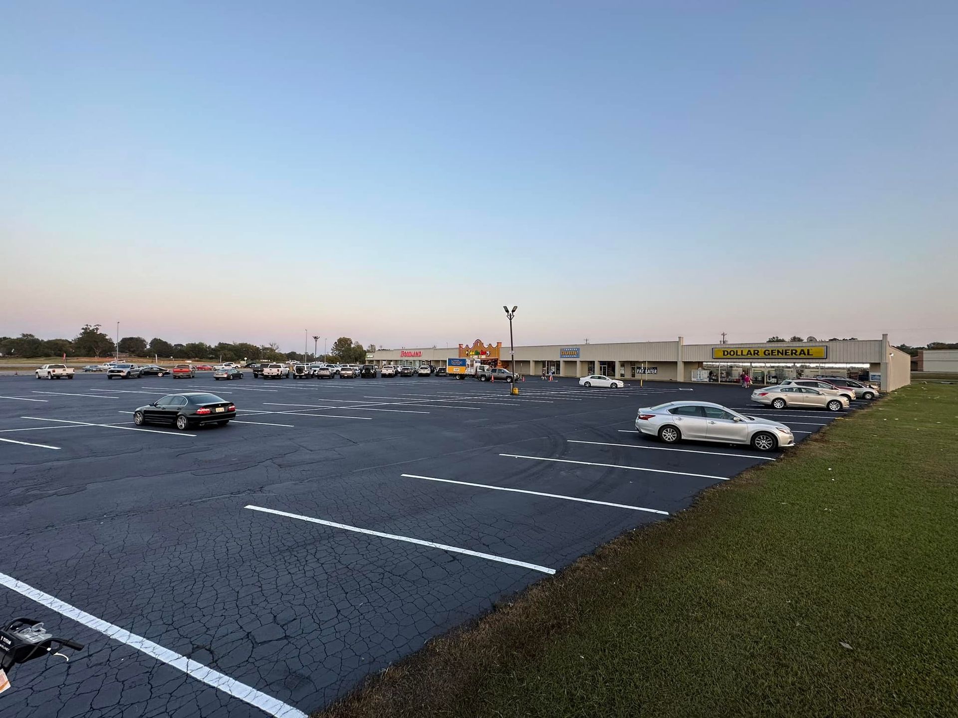 A parking lot with several cars parked in it, building in the background.