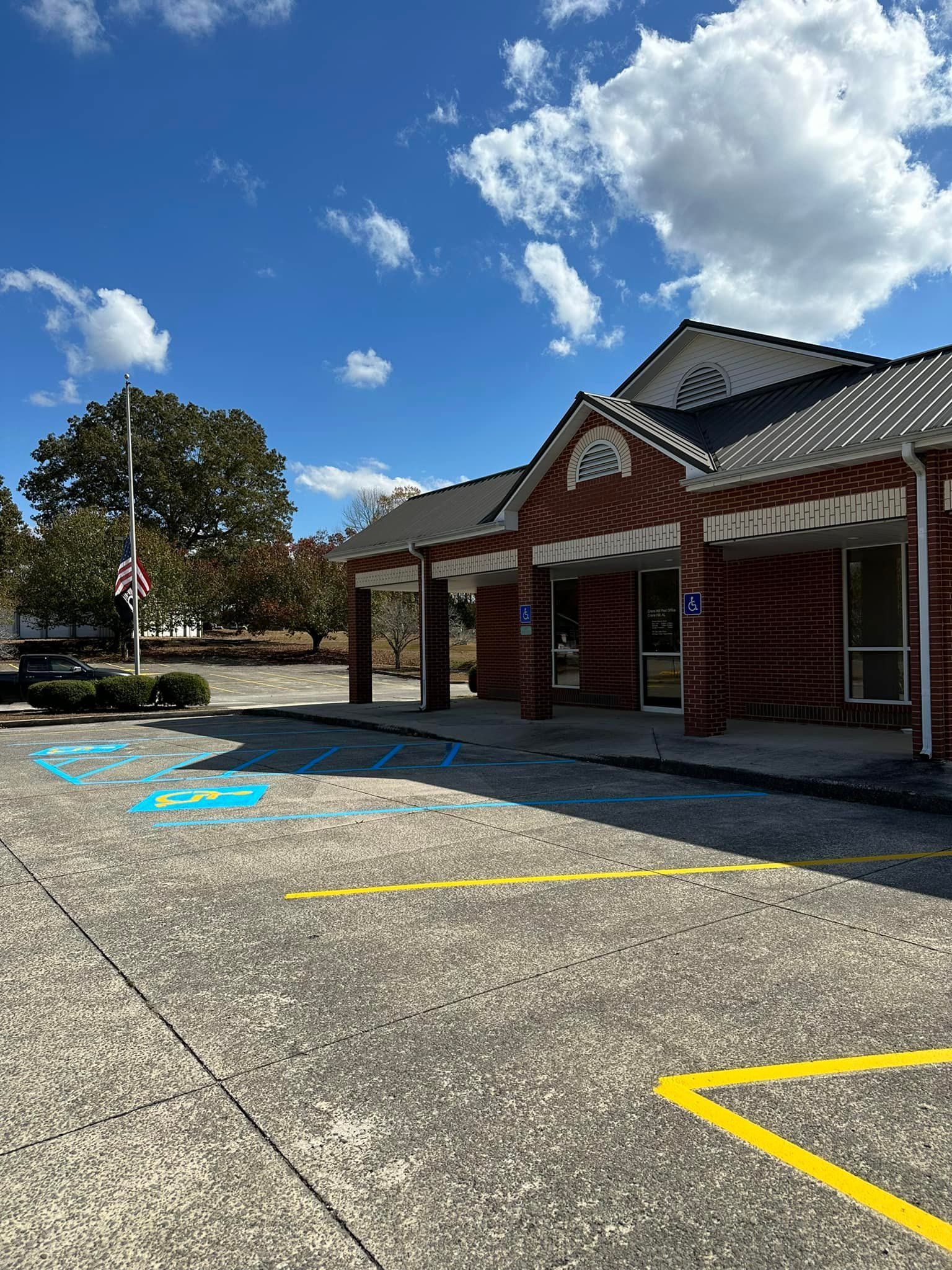 Exterior of a brick building with accessible parking spots marked with blue paint on a sunny day.