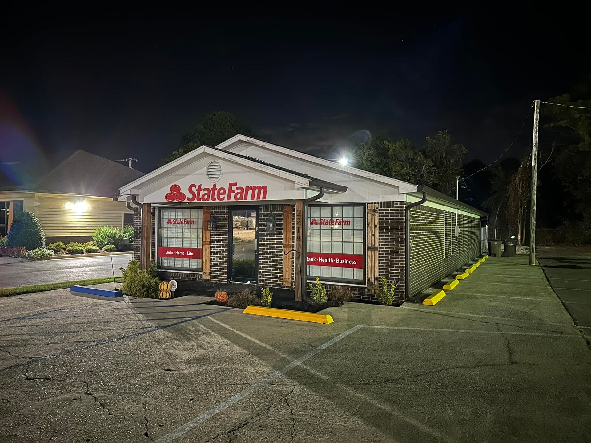 State Farm office at night, exterior view; building with sign and windows, lit parking lot.