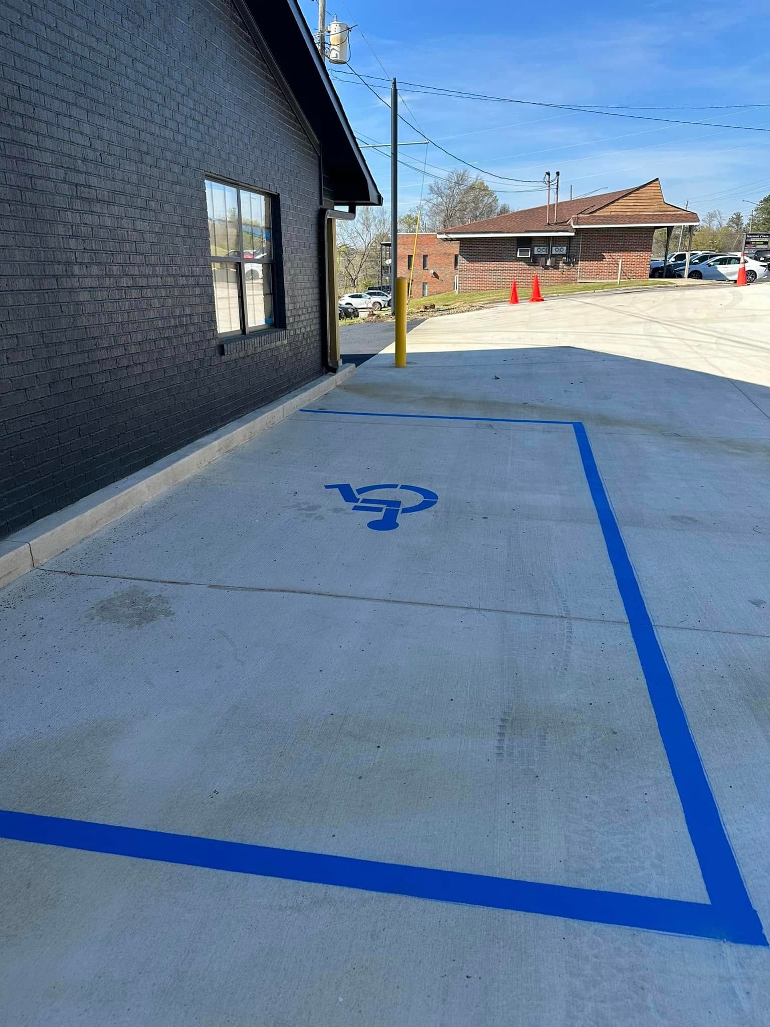 An accessible parking space with blue painted lines and a wheelchair symbol, next to a black building.