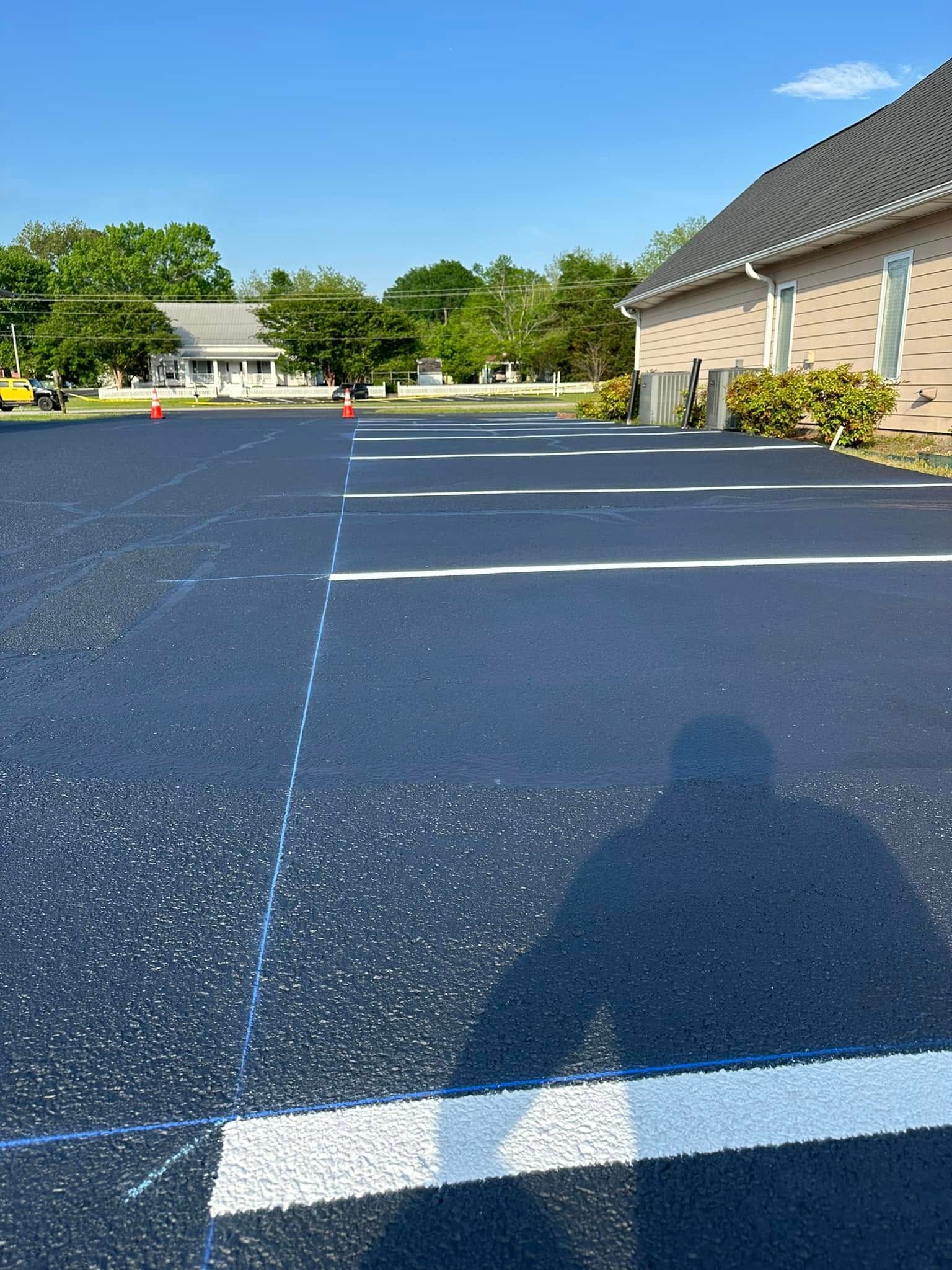 Parking lot with freshly painted white parking space lines; a shadow falls on the pavement.