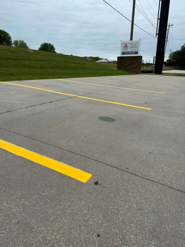 Yellow parking lines painted on gray asphalt; a sign in the background.