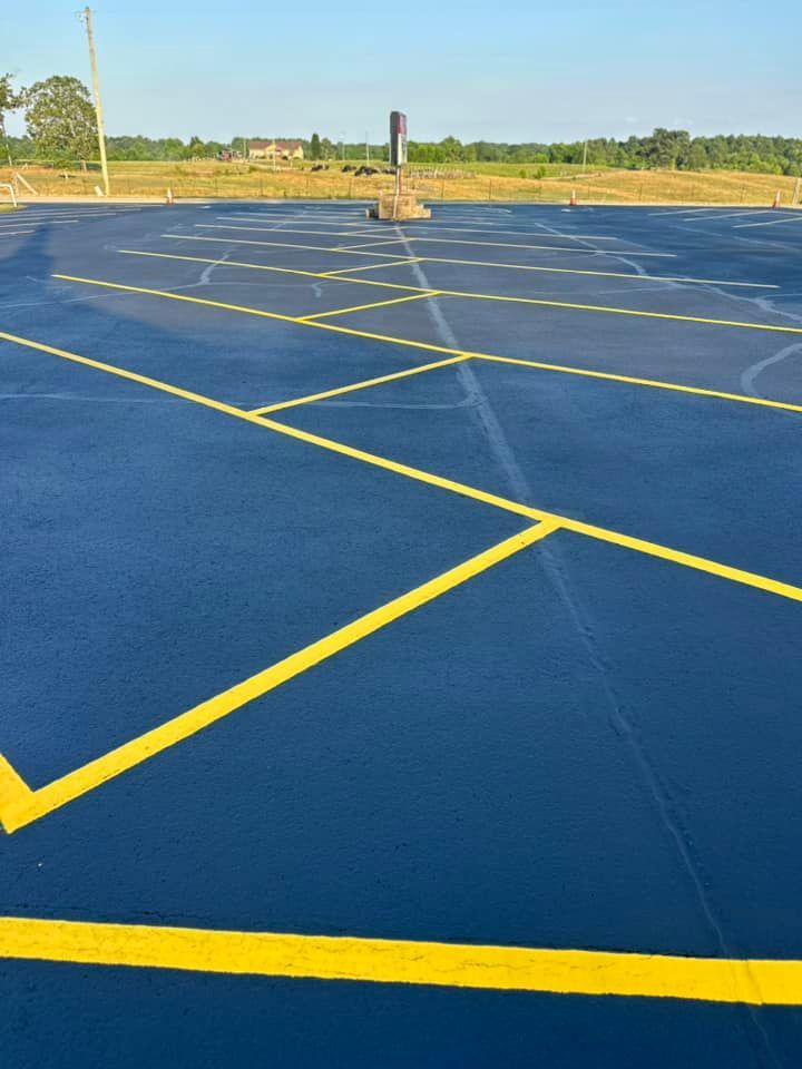Blue sports court with yellow lines, a small structure in the background, and a clear sky.