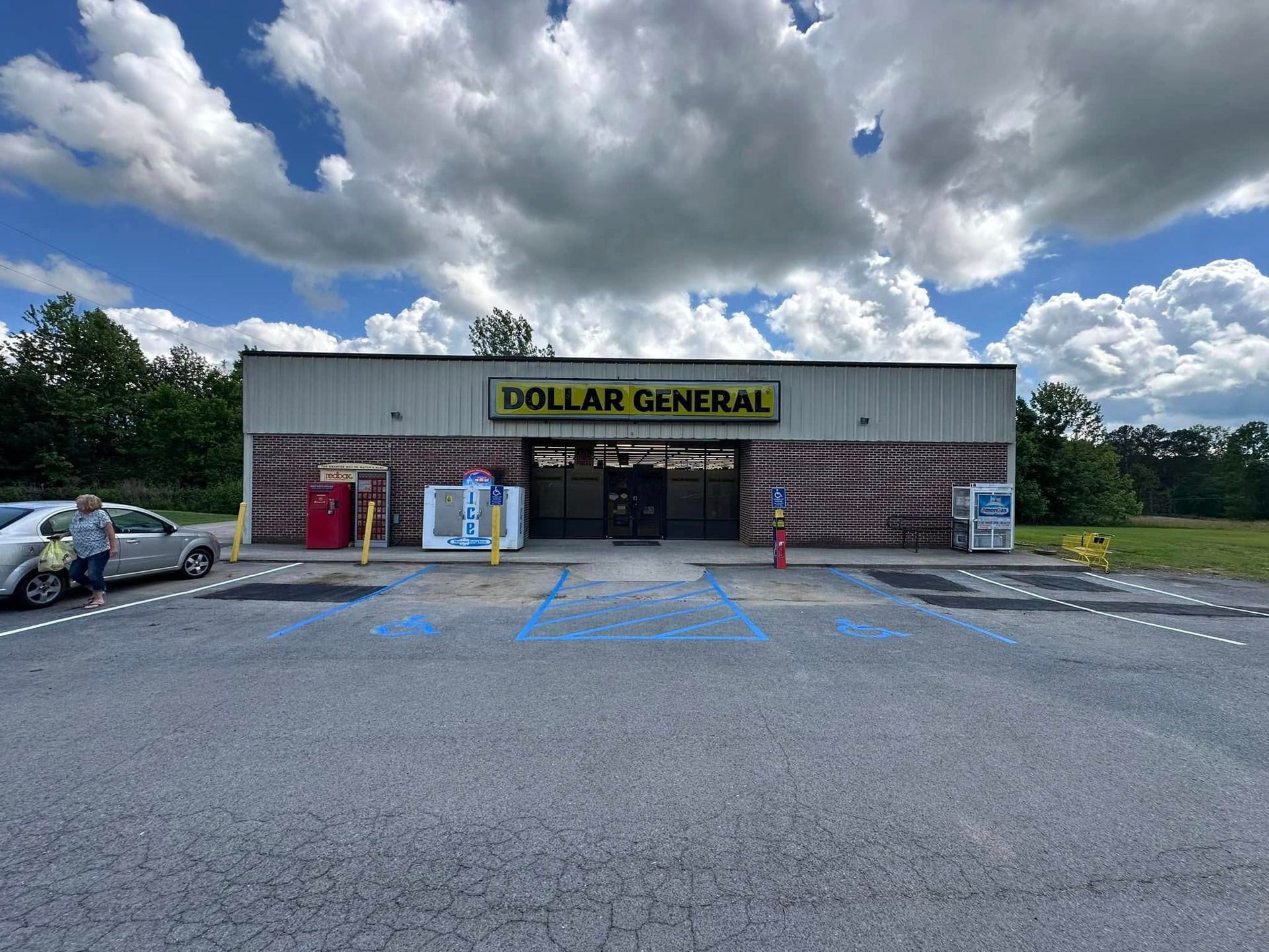Dollar General store front with parking spaces, blue sky, and a few clouds.