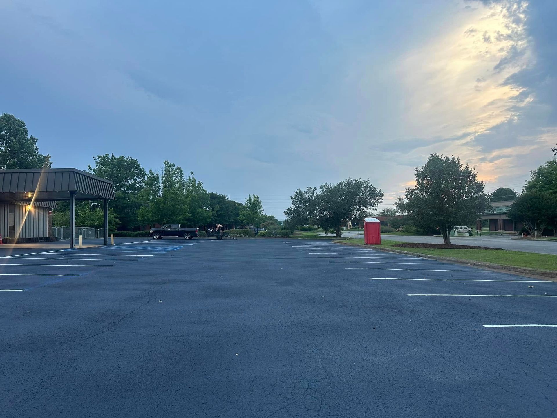 Empty paved parking lot with white parking space lines under a cloudy sky.