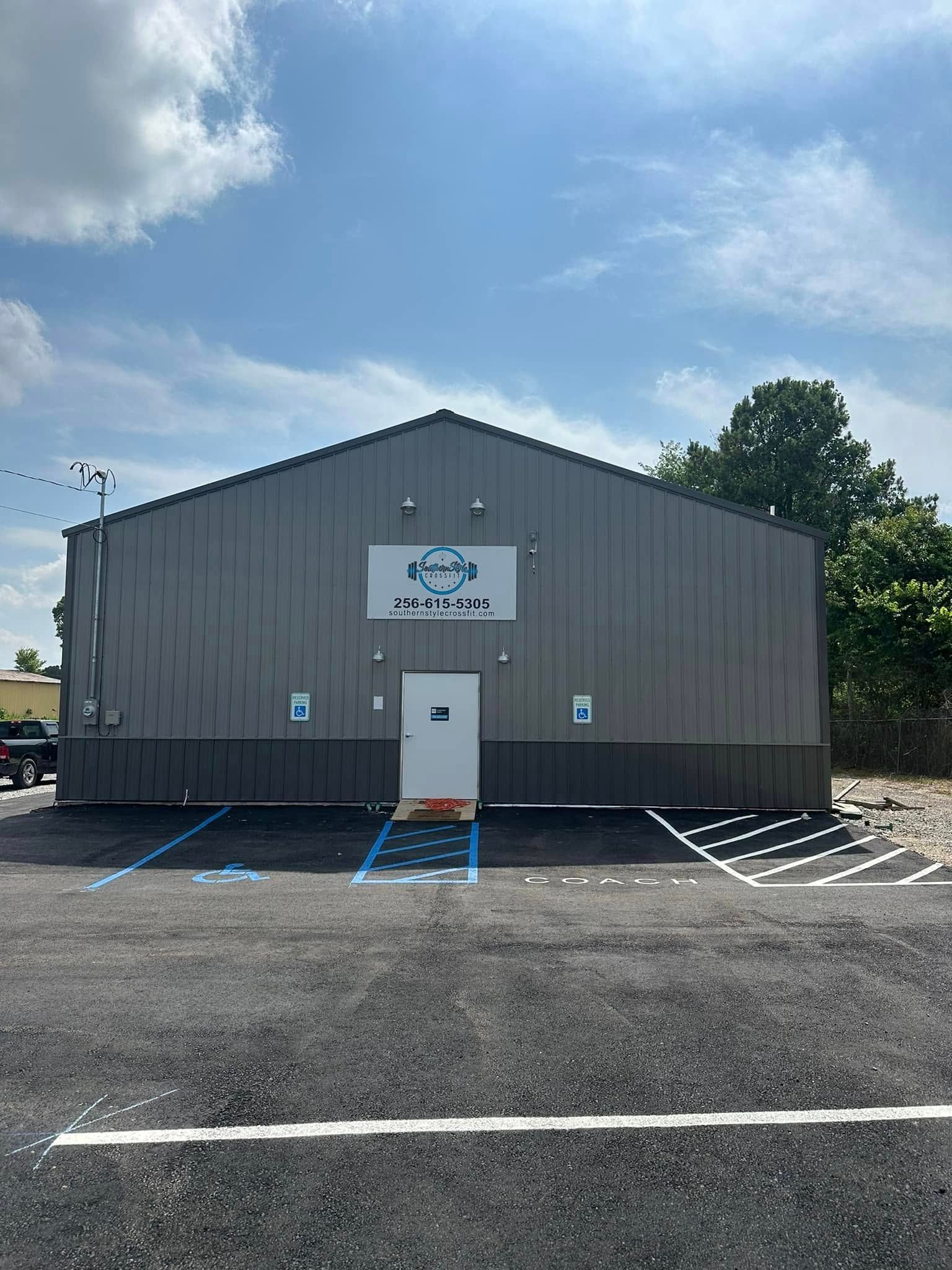 A gray metal building with a sign that reads “Joe’s Gym”. Accessible parking spots in front.