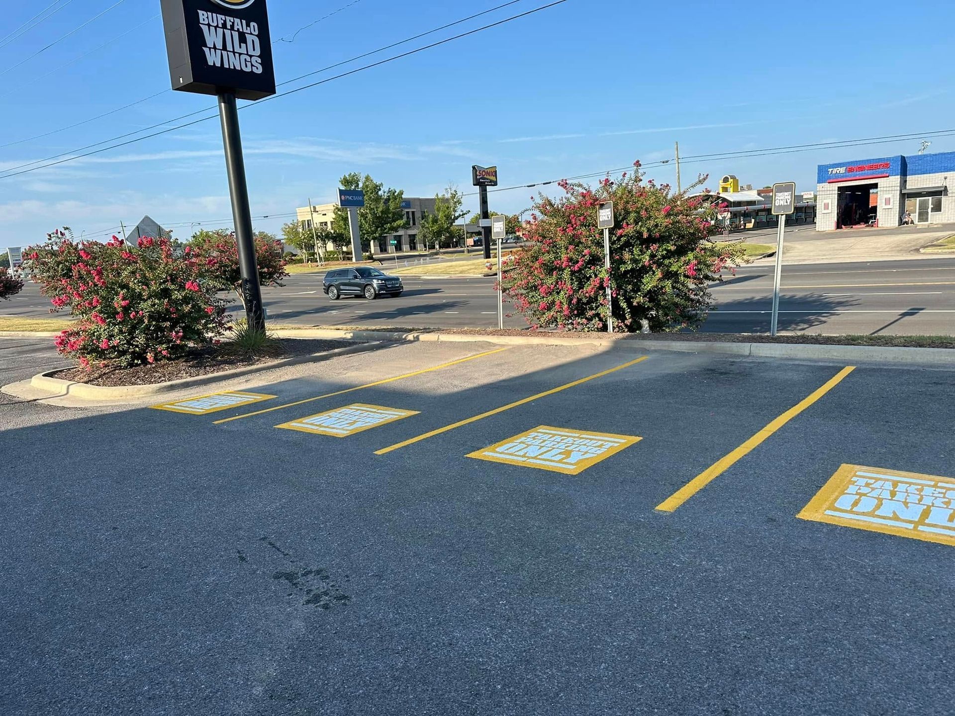Parking spaces in front of a business with bright signage and landscaping. Sunny day.