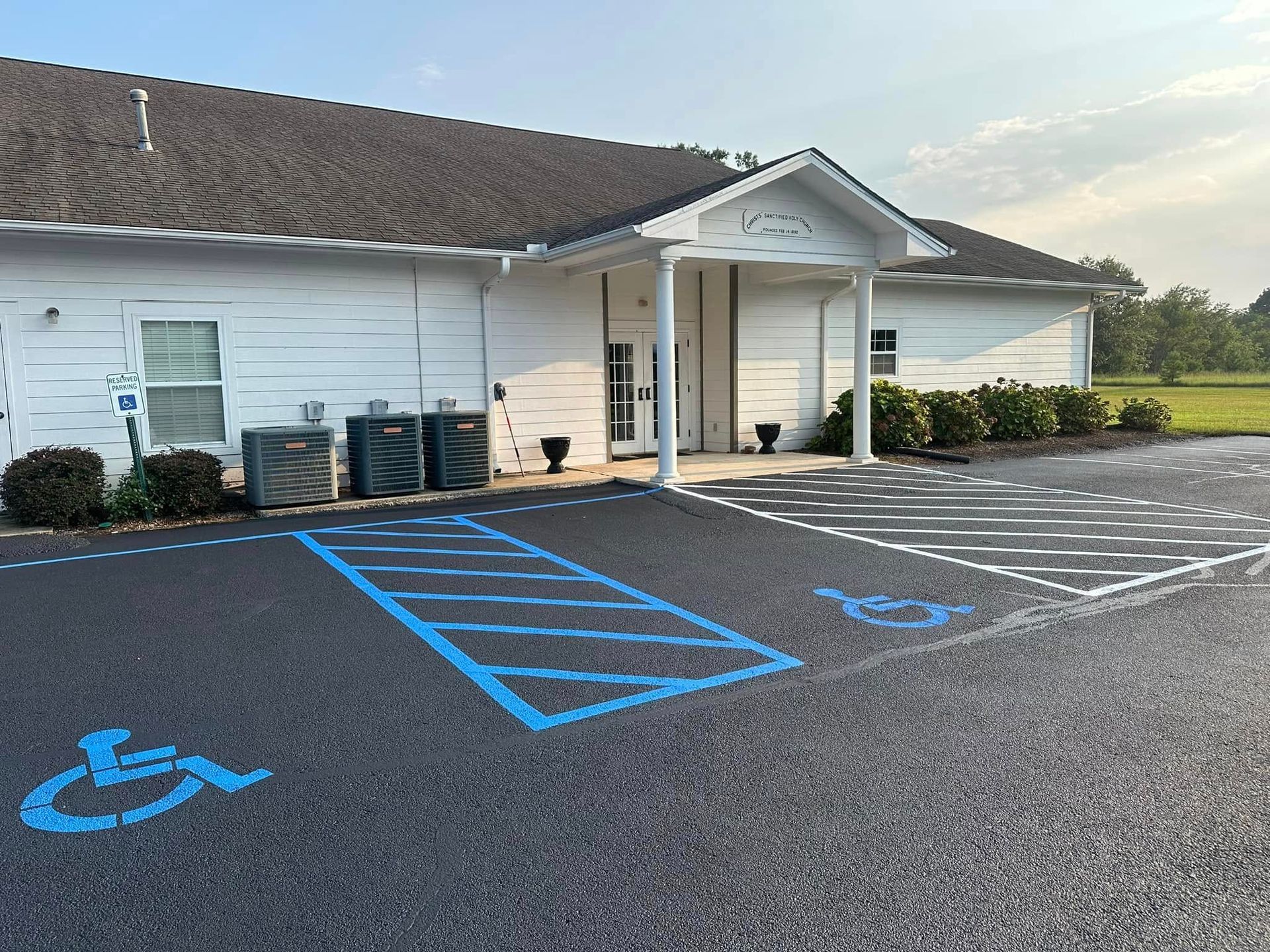 Exterior view of a white building with accessible parking spots marked in blue.