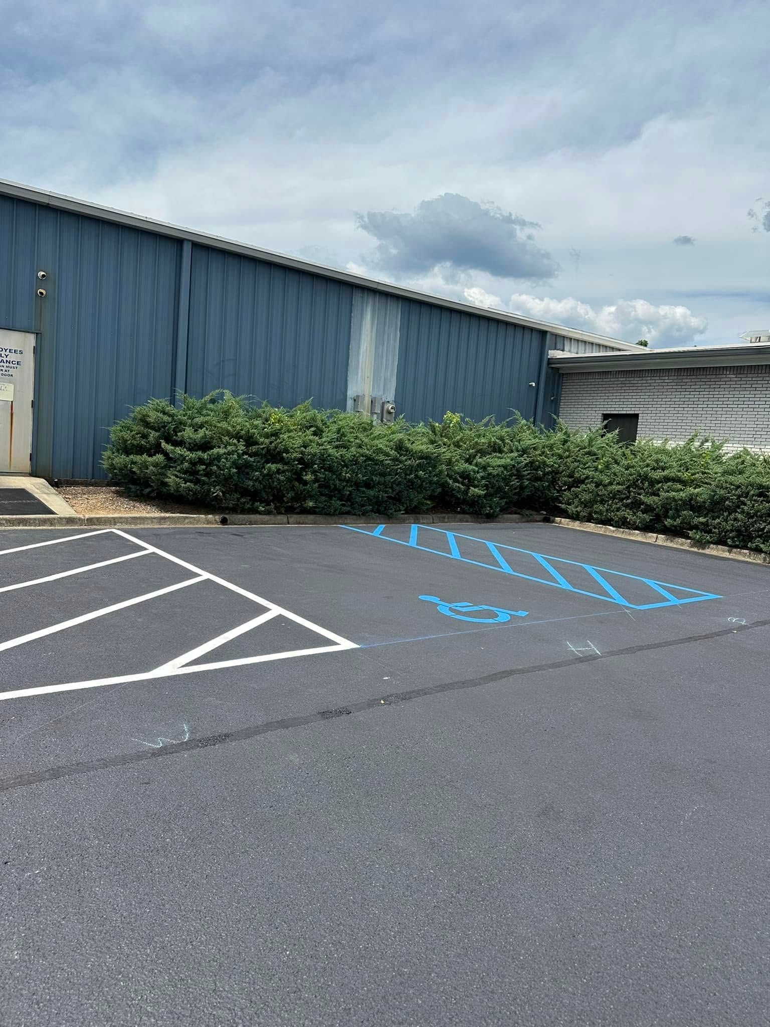 Exterior view of a building with blue metal siding, a parking lot, and a handicap parking space.