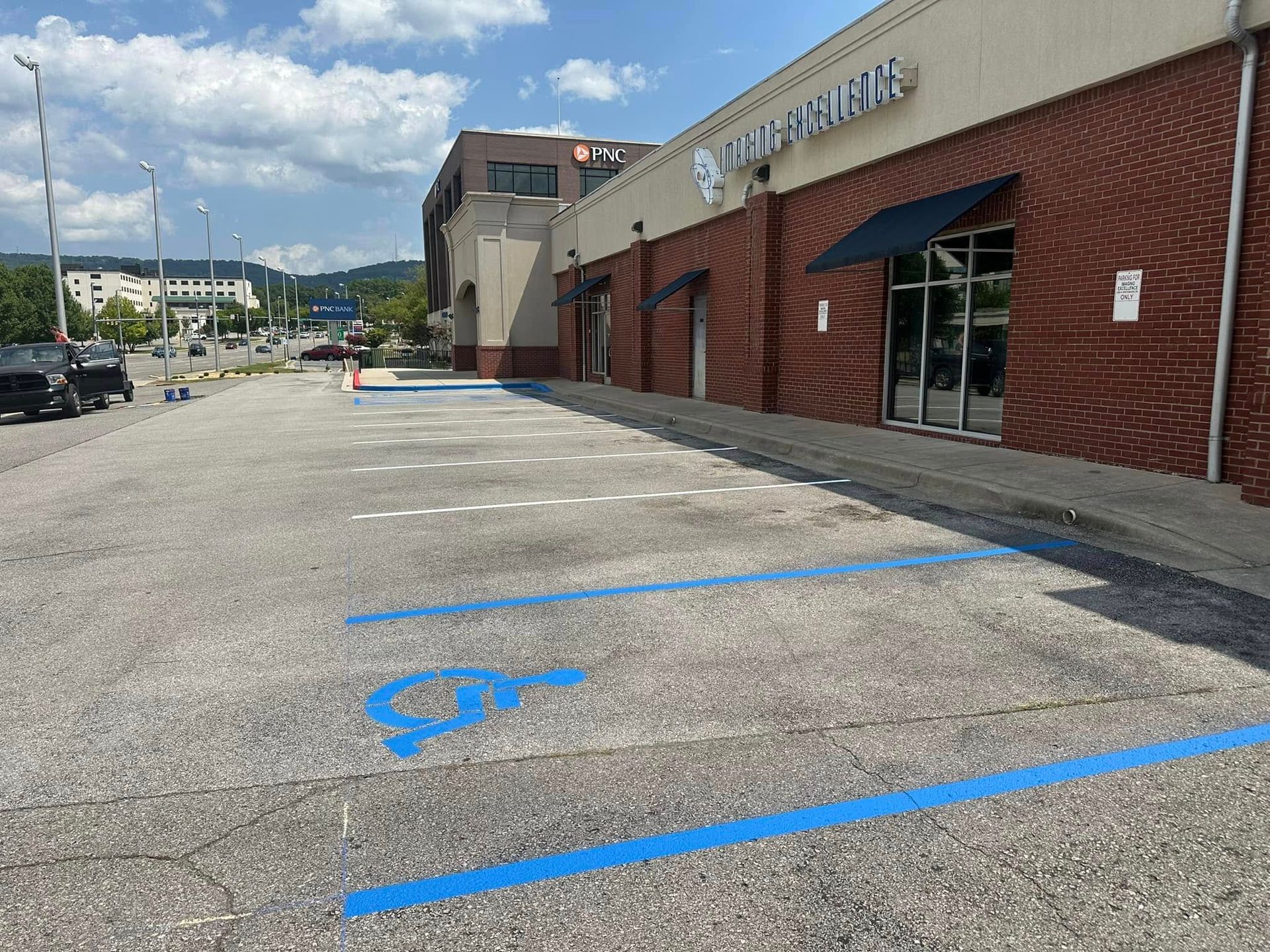 Parking lot with blue handicap space markings and store with brick facade.